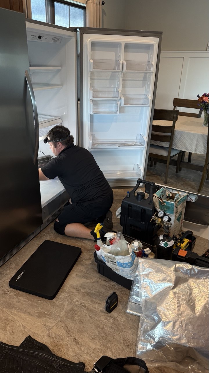 Technician inspecting a household refrigerator